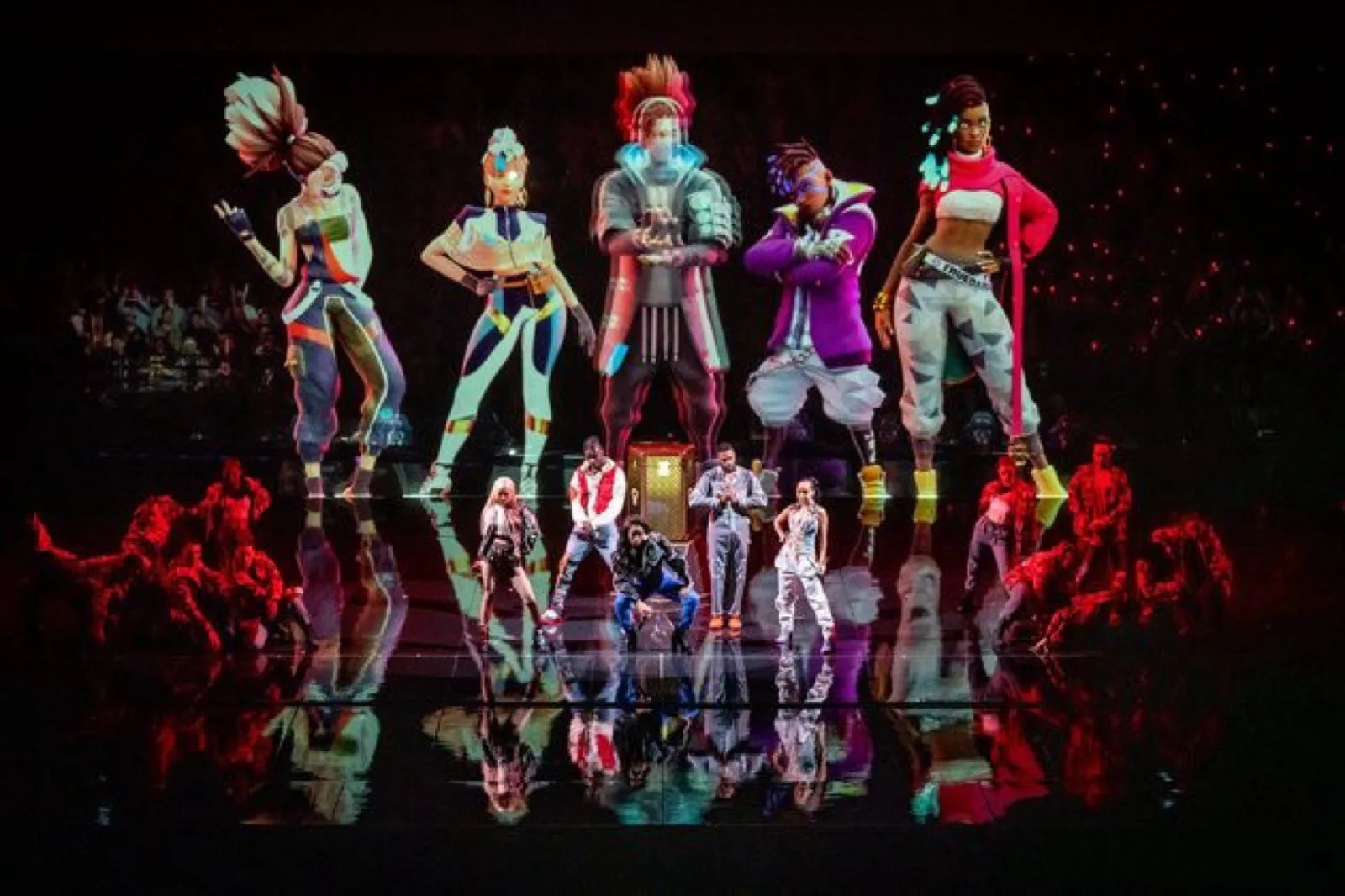 Augmented-reality performance of virtual League of Legends champions towering over live dancers and performers on a darkened stage