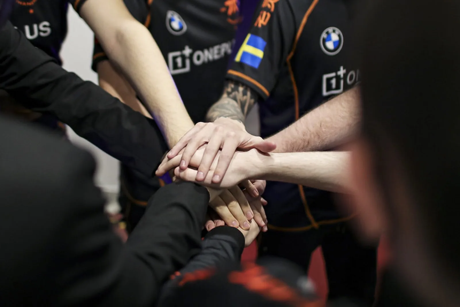 Players in sponsor-branded team jerseys stacking their hands together in a team huddle