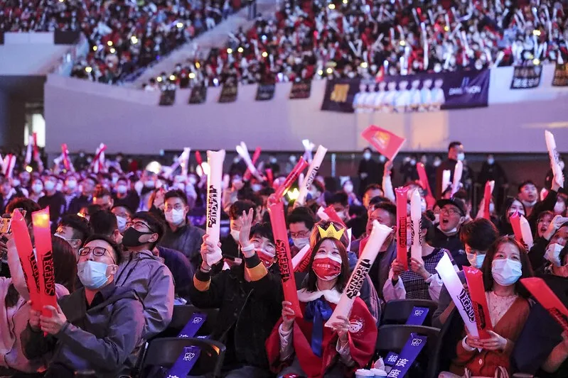 Masked fans cheering with thunder sticks in a packed arena at the League of Legends World Championship 2020 in Shanghai